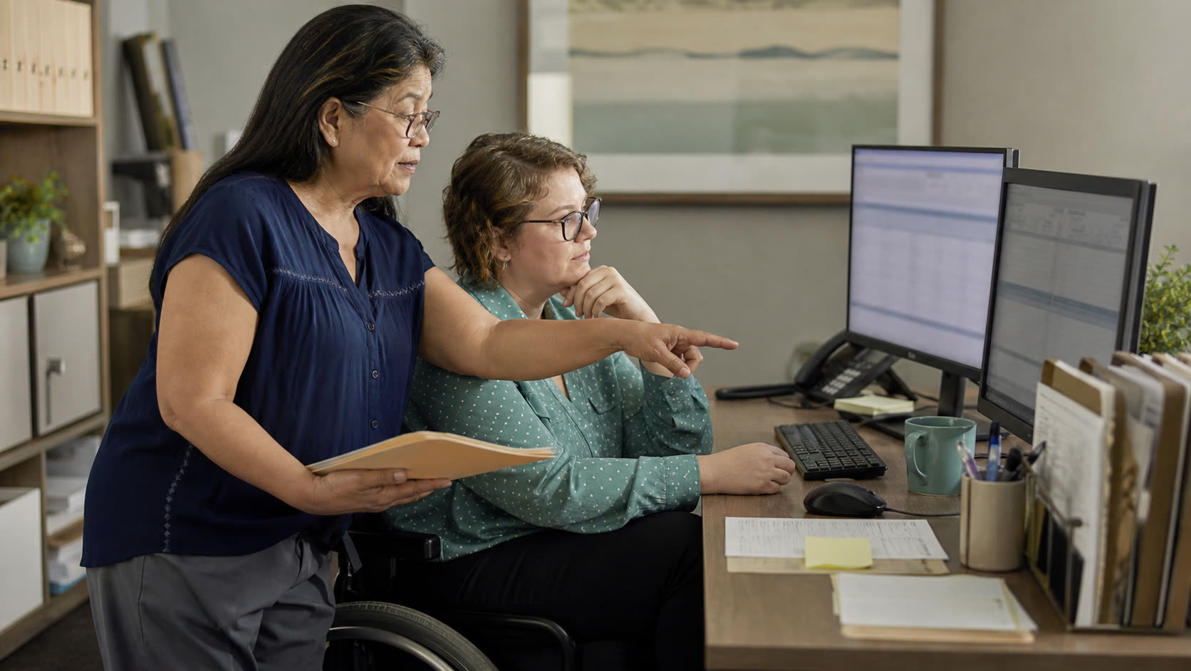 An experienced medical biller and a colleague reviewing a prepared work queue together, with the human biller choosing the next action.